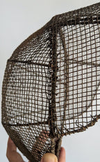 Close-up of hand-woven iron wire mesh on antique French fencing mask