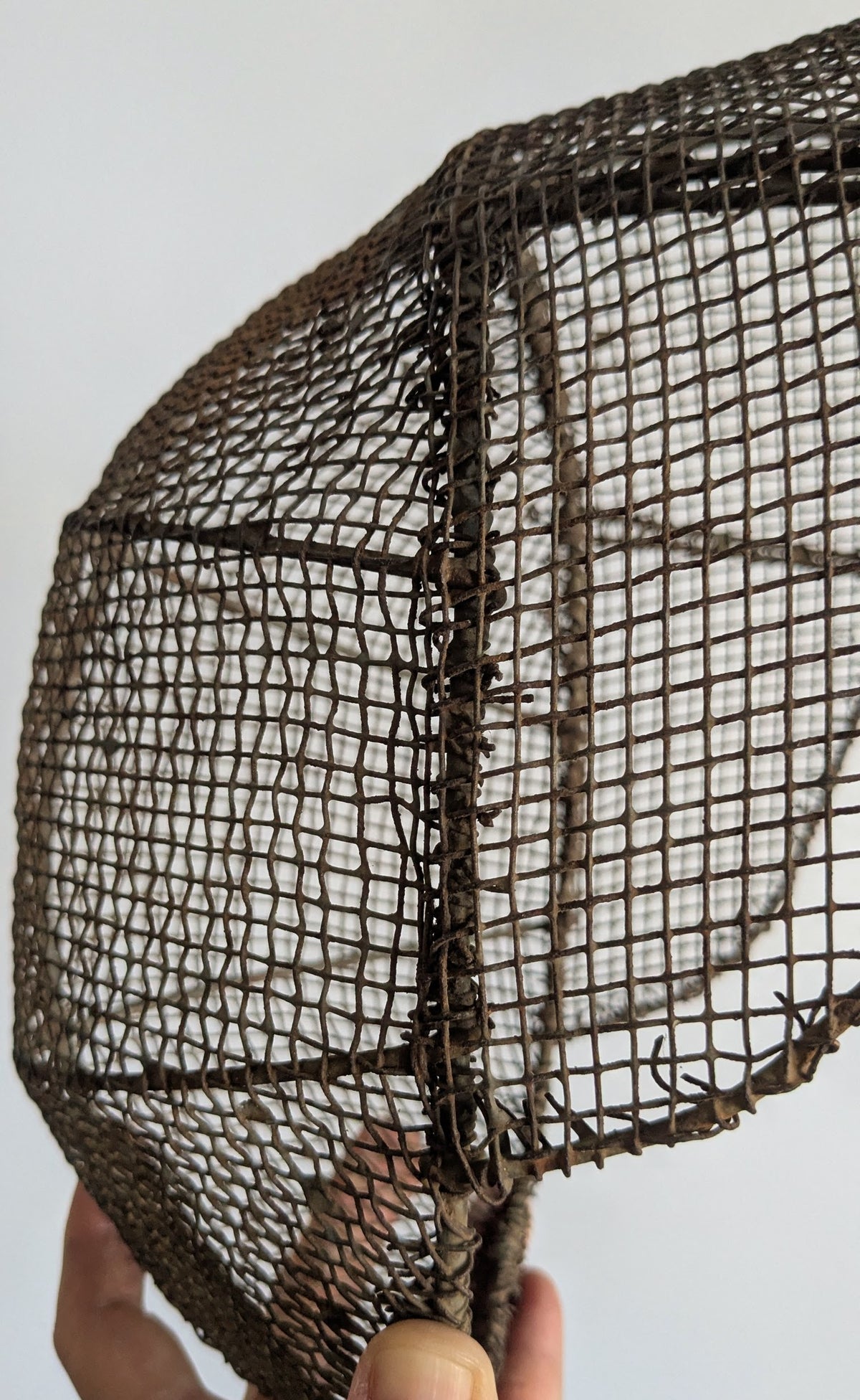 Close-up of hand-woven iron wire mesh on antique French fencing mask