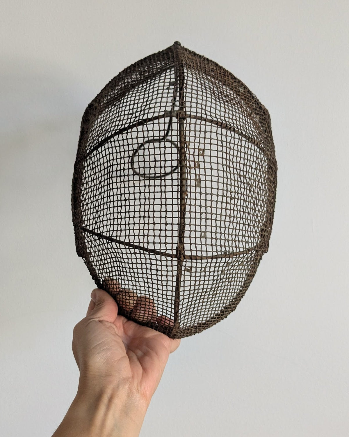 Front view of antique French fencing mask with aged iron wire mesh