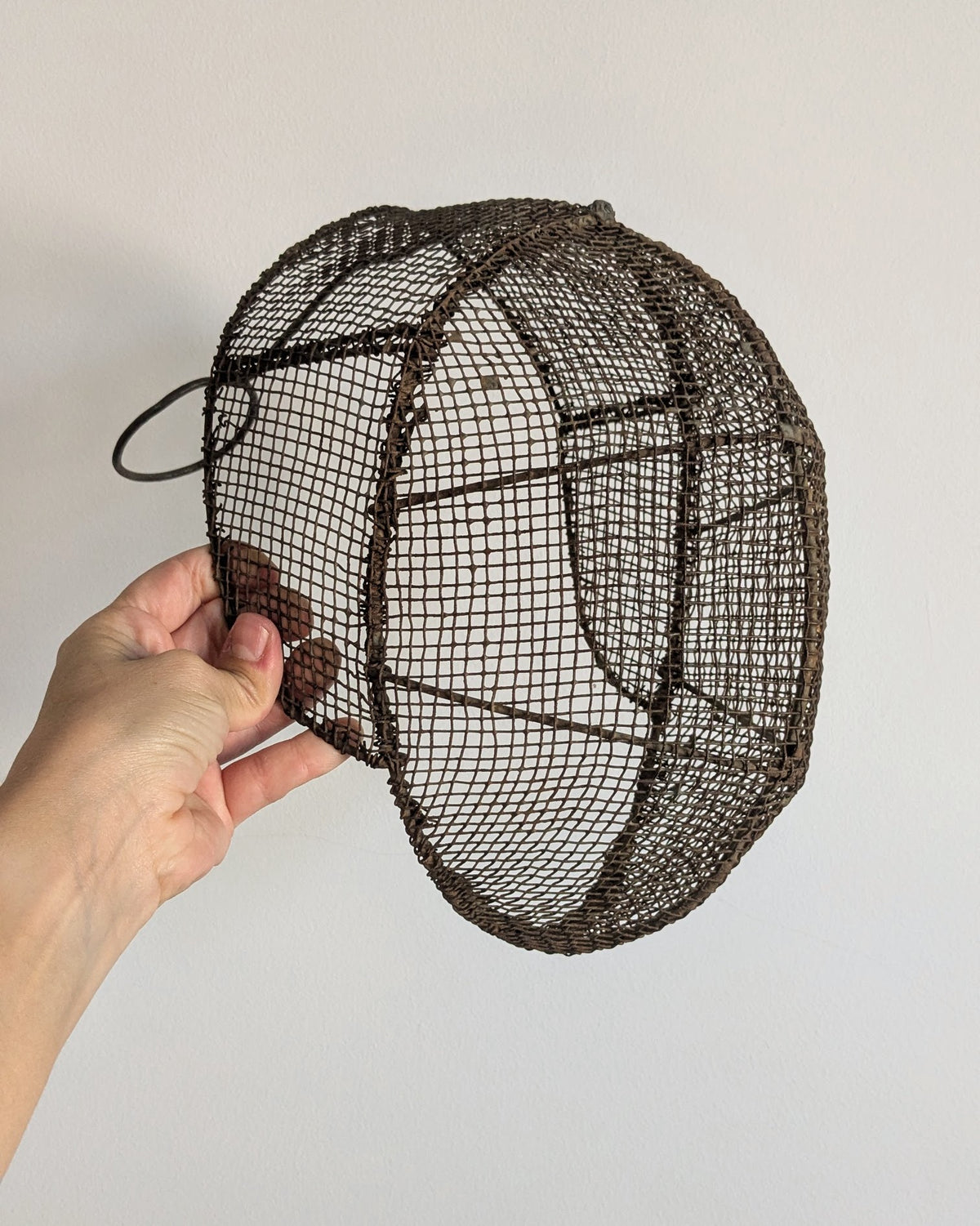Side view of antique fencing mask showing original rear support and oval strap loop